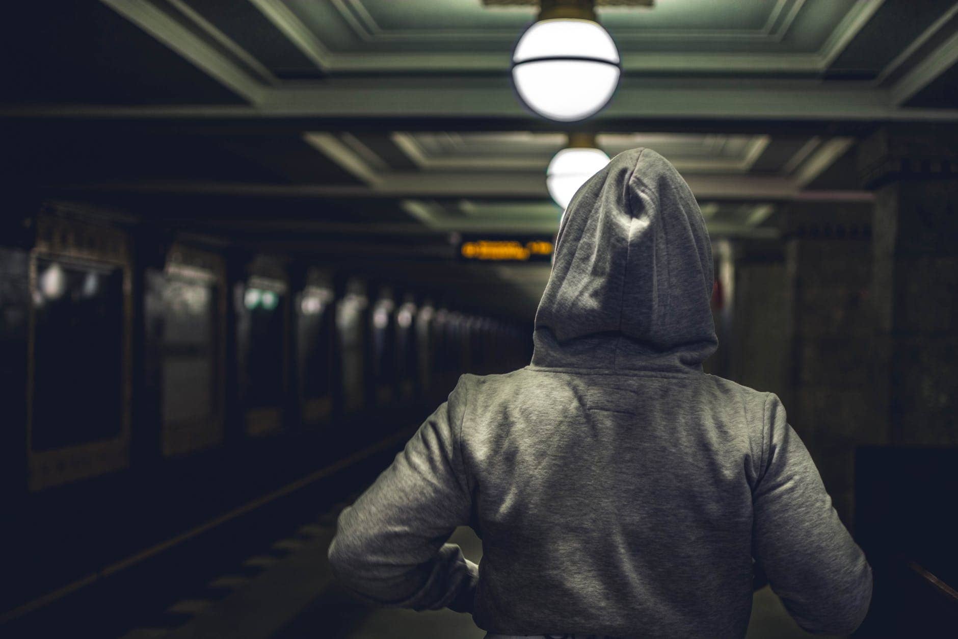 person wearing gray hooded jacket in train station